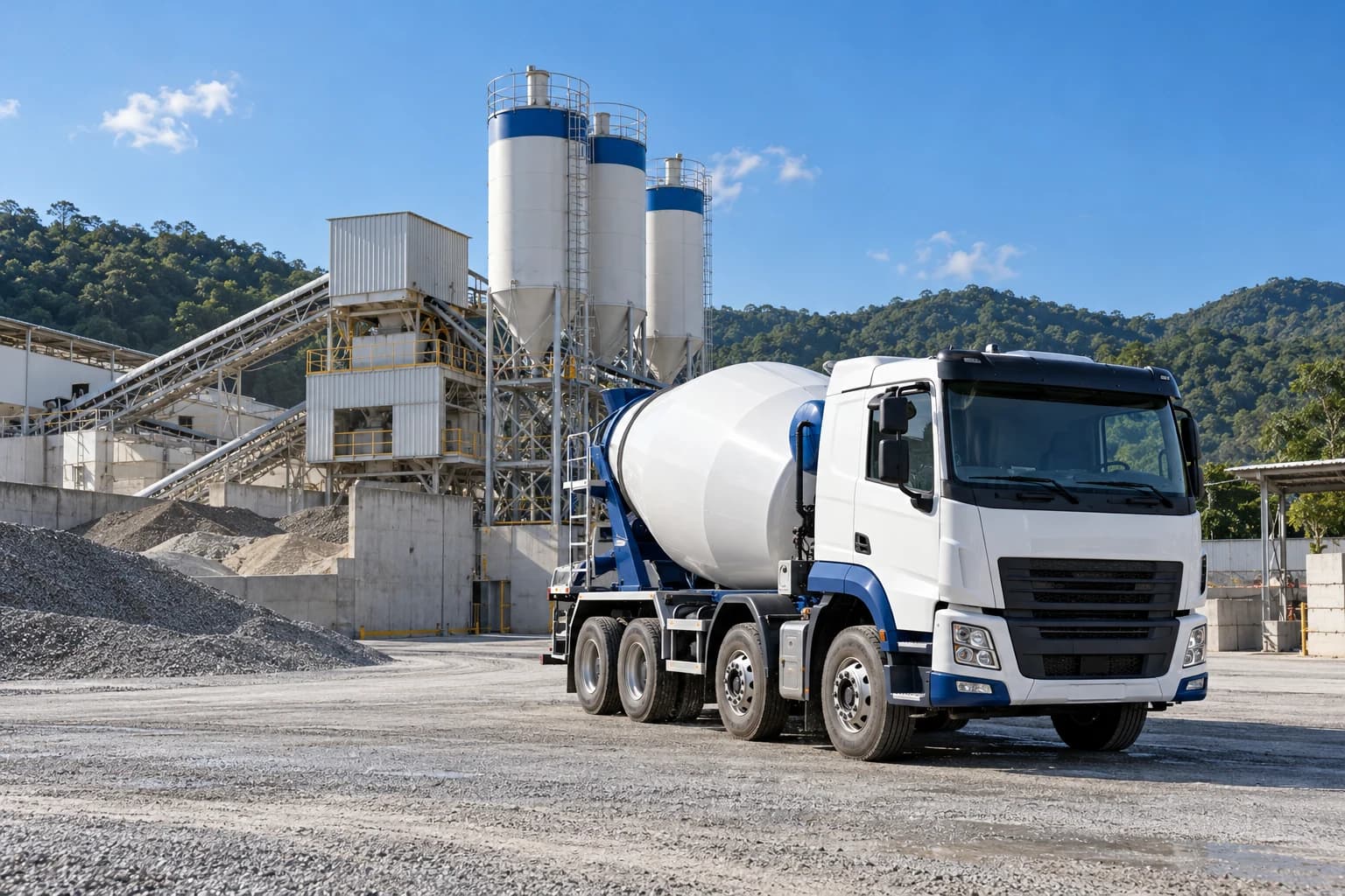 Caminhão betoneira em uma central de concreto organizada, com silos e área de produção ao fundo